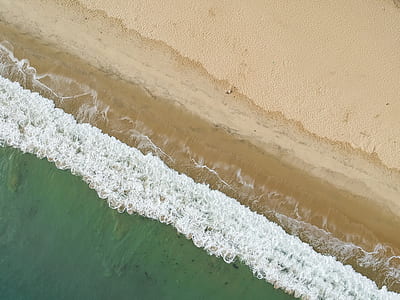bird's eye view photo of waves crashing on shore during daytime thumbnail