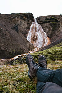 Feet relaxing on moss grown rock with waterfall in the background thumbnail