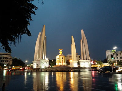 monument between high-rise building at night time photo thumbnail