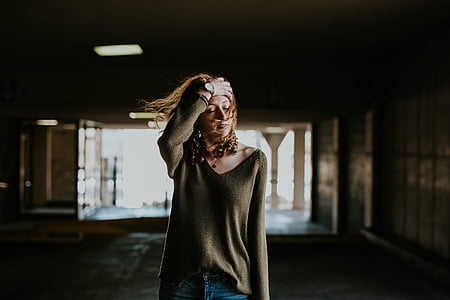 woman holding her head inside dark room thumbnail