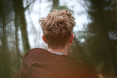 man wearing brown jacket facing trees thumbnail