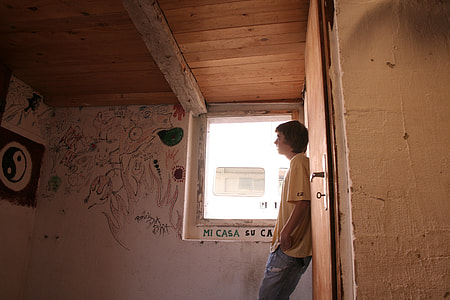 man in yellow crew-neck t-shirt standing near white wall paint with artwork thumbnail