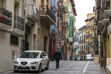 man walking beside parked white SEAT Leon on alleyway at daytime photo thumbnail