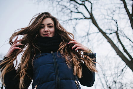 woman standing behind leafless tree thumbnail