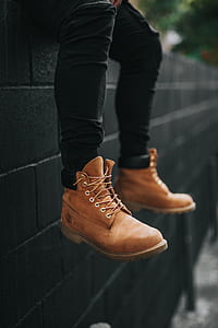 person wearing black fitted jeans and brown Timberland work boots sitting on fence thumbnail