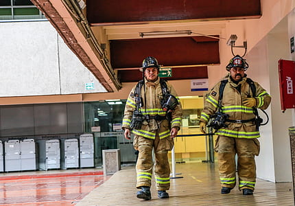 two firefighter walking on pavement beside wall thumbnail