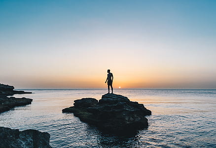 silhouette of a person on top of large rock soak in water at daytime thumbnail