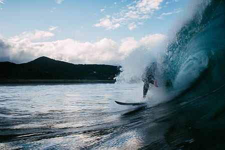 photo of person performing surfing near ocean wave during daytime thumbnail