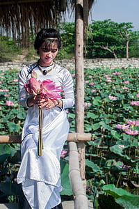 woman holding a pink petaled flower setting on hut thumbnail