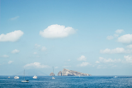 sail boat near island under blue sky thumbnail