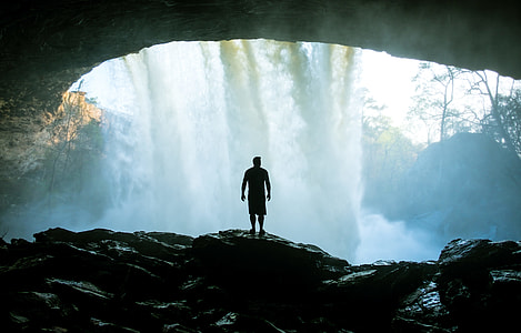 silhouette of man inside waterfall cave thumbnail