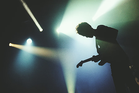 Man playing a guitar in concert lights thumbnail