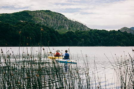 two person riding on boat on calm body of water near mountain thumbnail