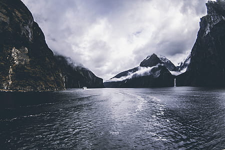 Body of Water Surround by Mountains Under Cloudy Sky thumbnail