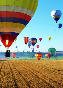 photograph of lot of hot air balloons flying above field of grass thumbnail