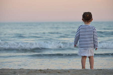 A child baby looking out to the ocean on the beach thumbnail