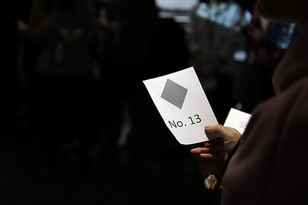 person holding paper with no. 13 thumbnail