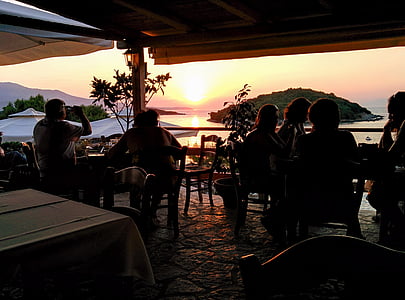 silhouette of group of person sitting near body of water thumbnail