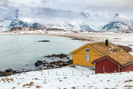 two yellow and red houses surround with mountains during winter season thumbnail