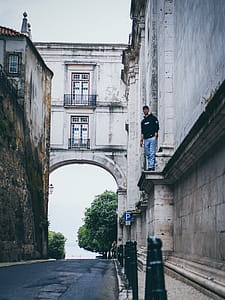 Man Wearing Black Pullover Hoodie Standing on Beside Beige Concrete Building thumbnail
