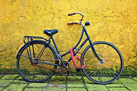 black bicycle beside yellow wall thumbnail