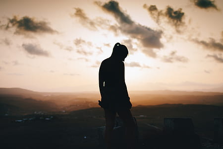 silhouette of person standing at the mountain near cliff thumbnail