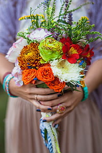 woman in purple and orange dress holding variety of flower bouquet thumbnail