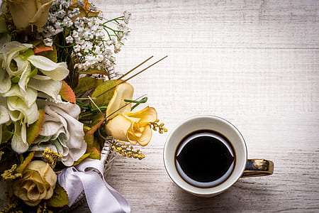 cup with black liquid beside bouquet of flowers thumbnail