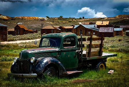 classic green pickup truck on green grass field in distant of houses thumbnail