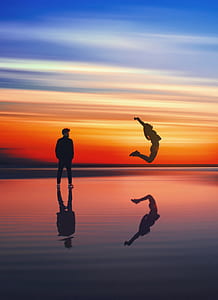 silhouette of woman and man standing on seashore photography thumbnail