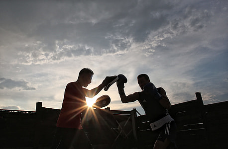 silhouette photo of two men training under gray clouds thumbnail