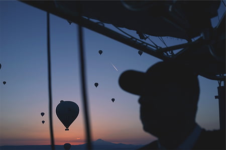 silhouette photography of man sitting inside the air balloon thumbnail