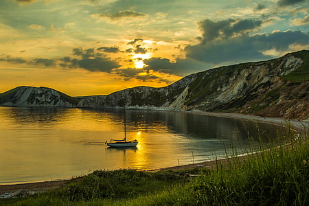 white boat on water near mountains during golden hour thumbnail