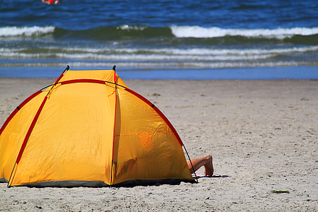 yellow and red dome tent on placed on gray sand seashore thumbnail