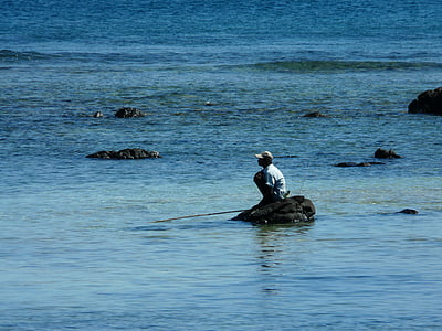 man sitting on rock in body of water thumbnail