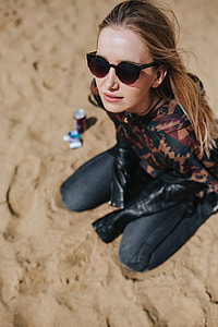 Young woman wearing a leather jacket and sunglasses on the beach thumbnail