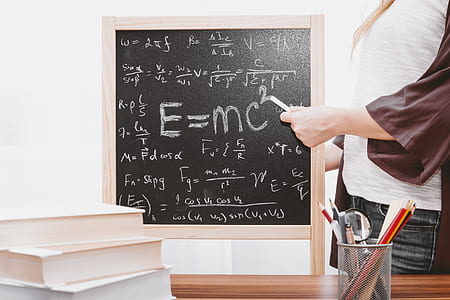 woman writing mathematical equations on blackboard using chalk thumbnail
