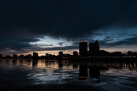 silhouette of city skyline near body of water thumbnail