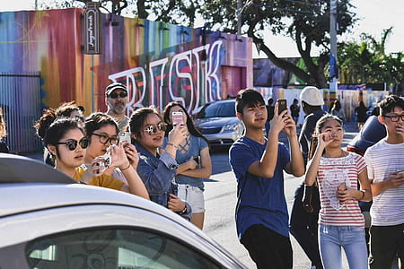 group of people standing while taking photo using phones thumbnail