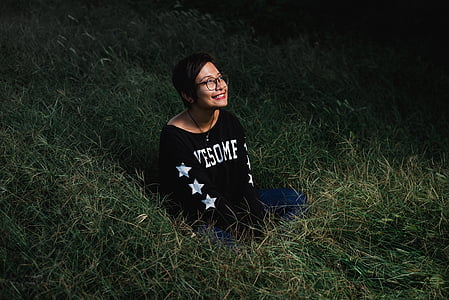 smiling woman sitting on green grass at night thumbnail