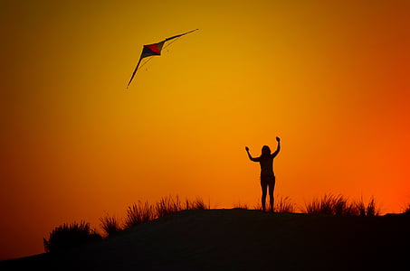 silhouette of woman flying kite thumbnail