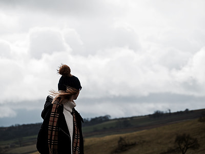 person in bobble cap and jacket with burberry scarf standing in open field area thumbnail