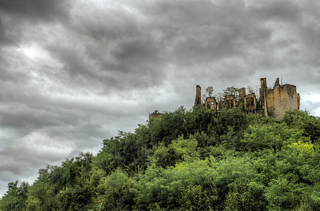 brown building on hill with green trees under grey sky at daytime thumbnail