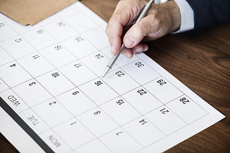 person holding click pen writing on calendar thumbnail