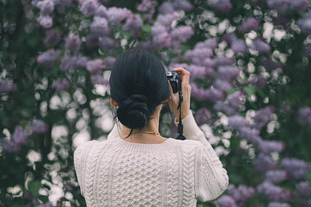 Woman Holding Camera Taking Photos of Flowers thumbnail