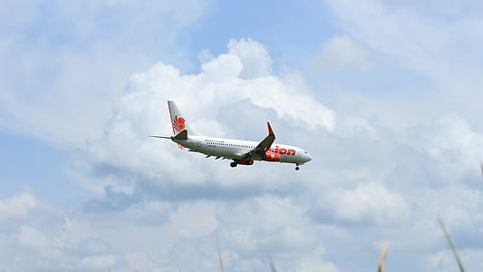 white and red passenger plane under white clouds at daytime thumbnail