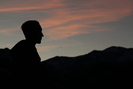 silhouette photography of man standing with background of mountain thumbnail