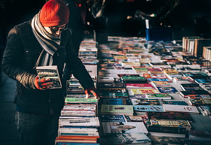 man standing in front of assorted-title books thumbnail