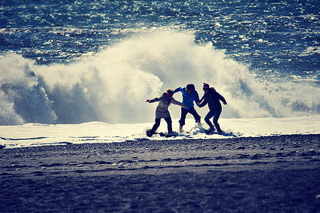 three children playing on seashore during daytime thumbnail