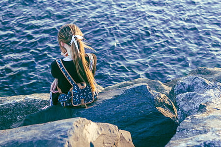 girl sitting on rock near sea thumbnail